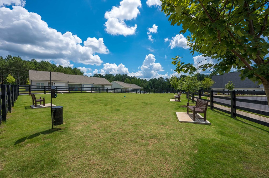 a park with benches in front of a fenced in field