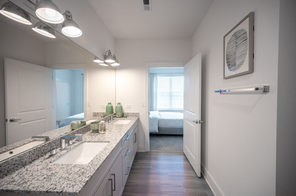 a bathroom with a sink and a mirror and a door to a bedroom