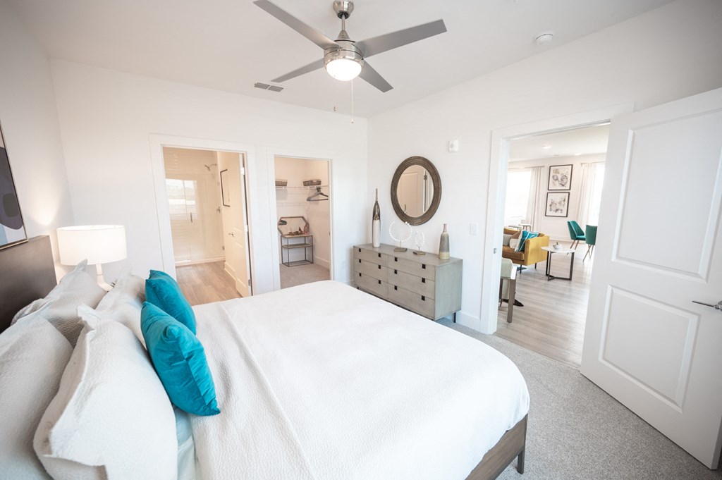 a bedroom with a large white bed and a ceiling fan