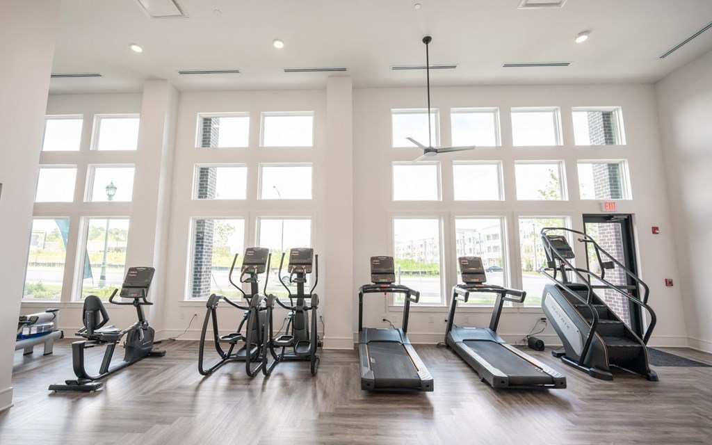 a gym with cardio equipment and windows in a building