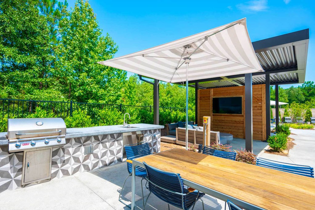 a backyard patio with a barbecue grill and a table with chairs