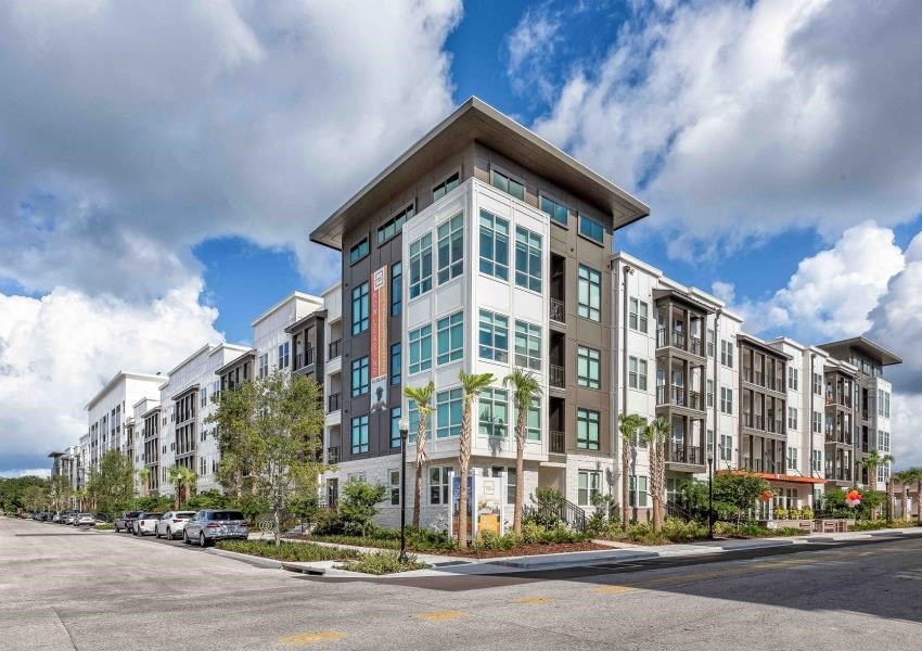a large apartment building on a street with a cloudy sky