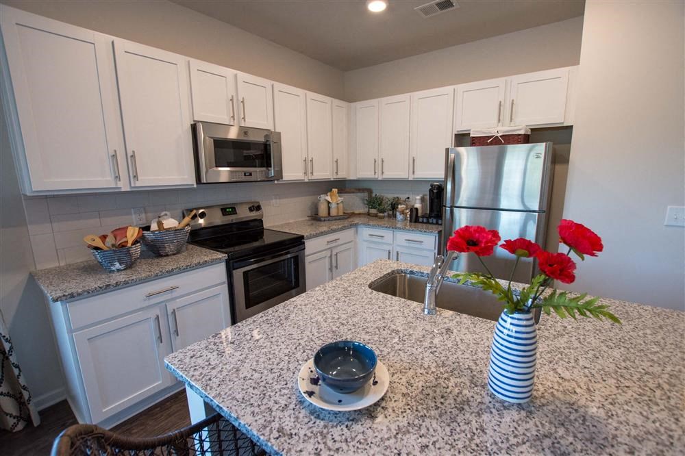 a kitchen with white cabinets and a granite counter top