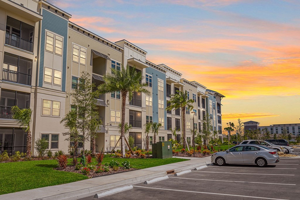 a car parked in front of an apartment building at sunset