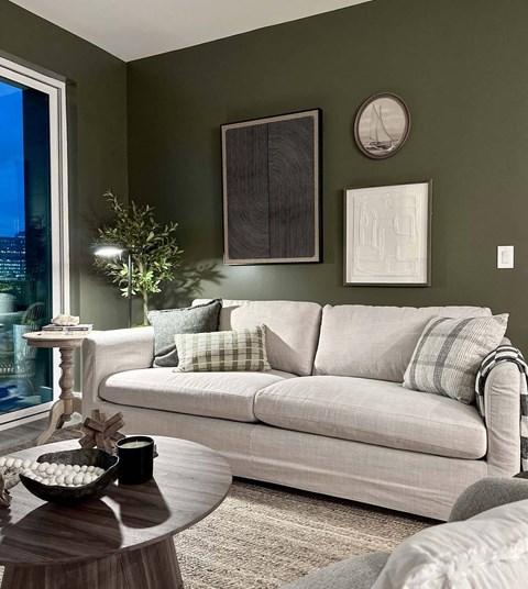 A living room with a white couch and a green wall.