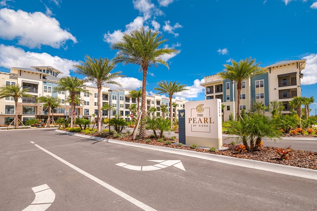 an empty parking lot in front of an apartment building with palm trees