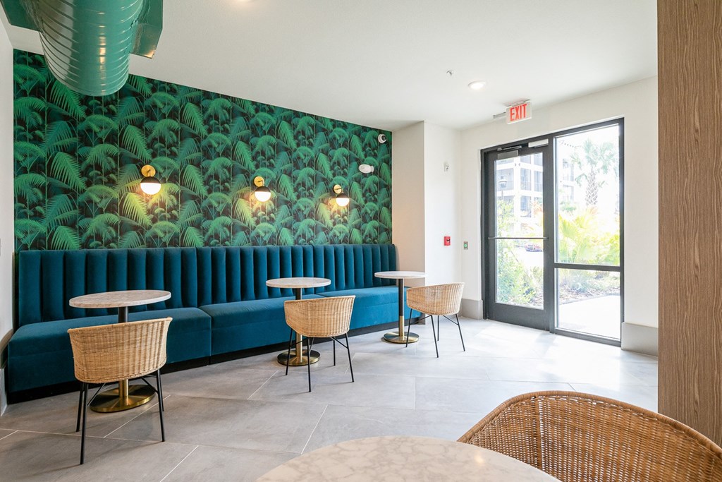 a lobby with blue couches and tables with chairs and a green wallpaper