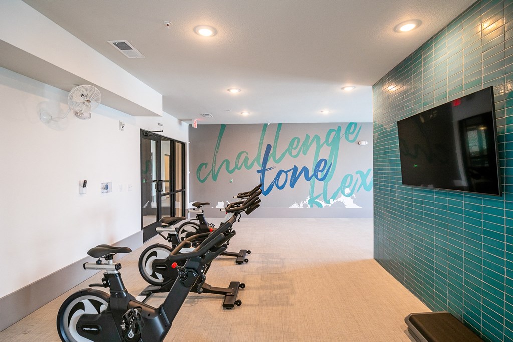 a workout room with exercise bikes and a television