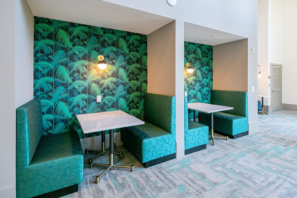 a lounge area with tables and chairs and a green wallpaper