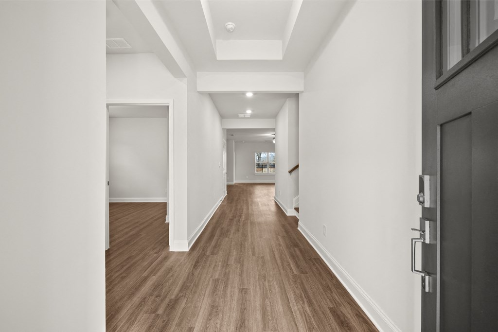 a living room and hallway with white walls and wood floors