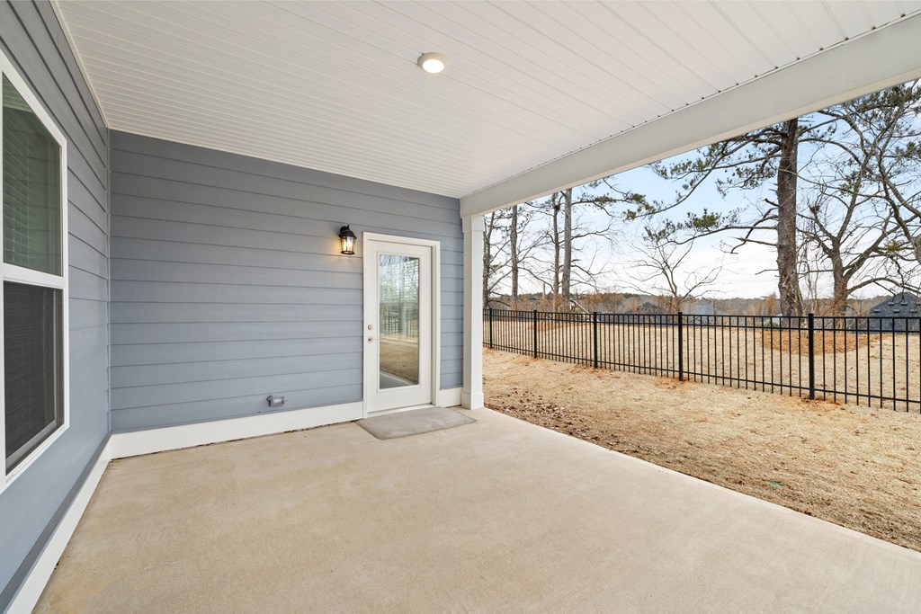 the front porch of a gray house with a white door and a black fence