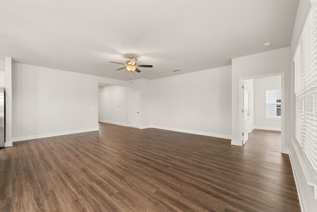 an empty living room with white walls and a ceiling fan