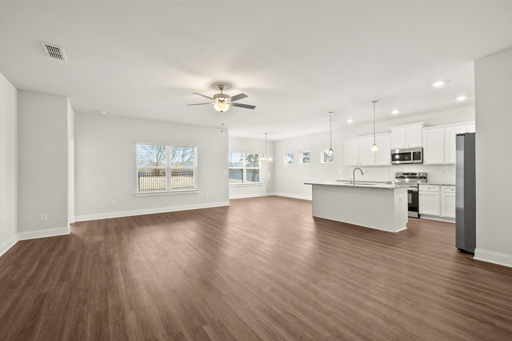 a living room with a kitchen and a ceiling fan