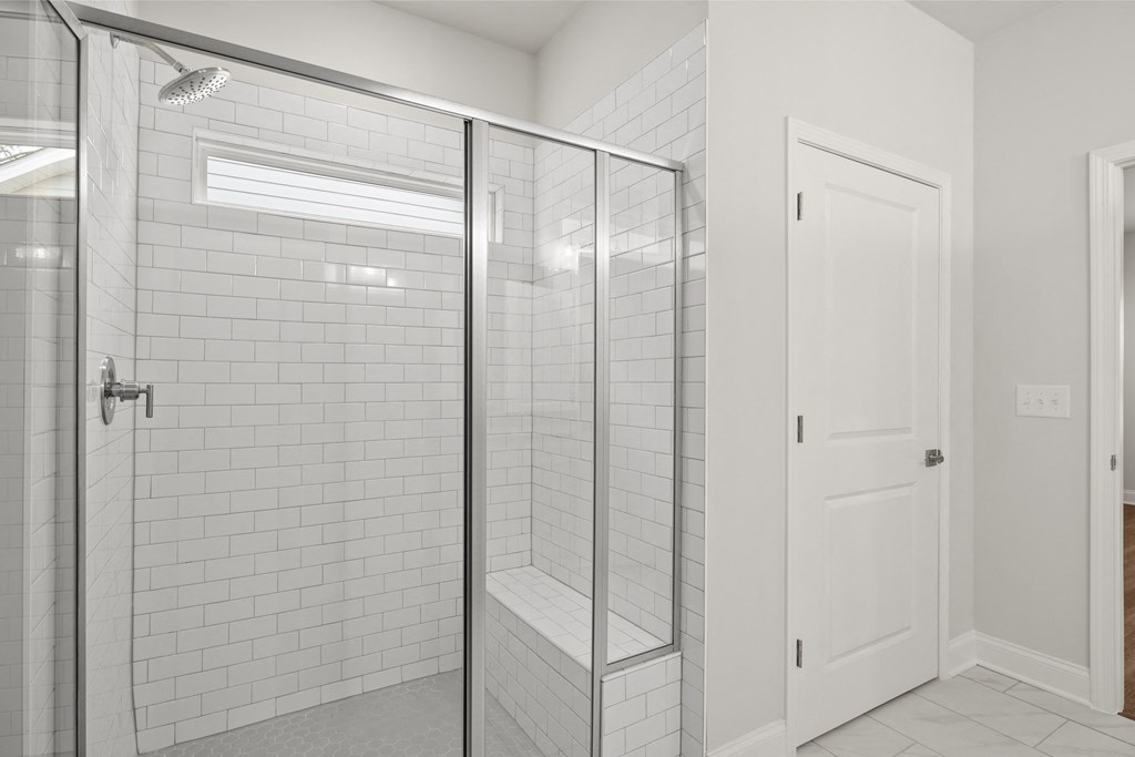 a white bathroom with a shower and a white door
