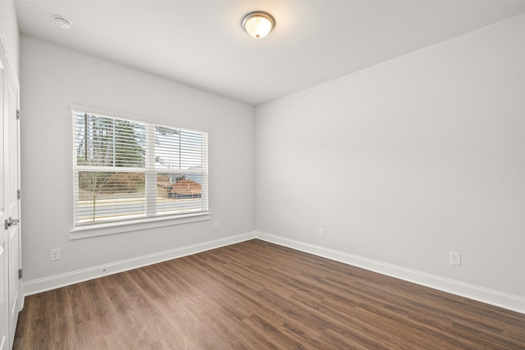 an empty living room with wood floors and a window