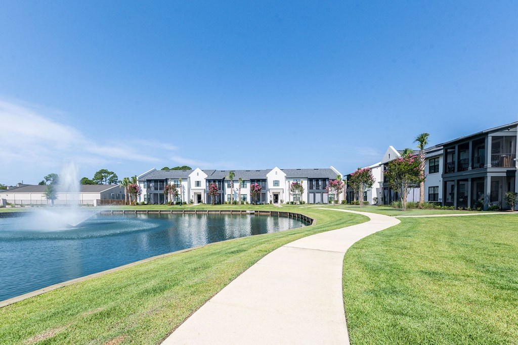 a walkway around a lake with apartments in the background