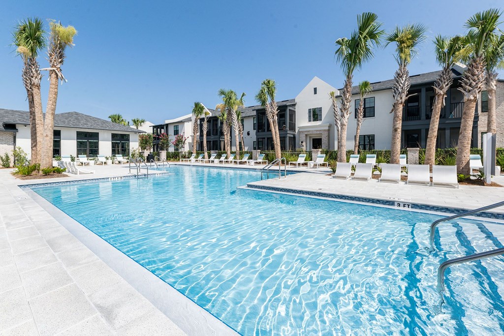 a swimming pool with palm trees and apartments in the background