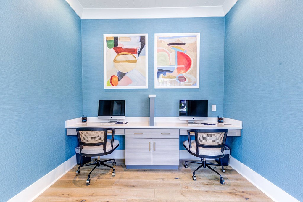 two desks with two monitors and two chairs in a room with blue walls
