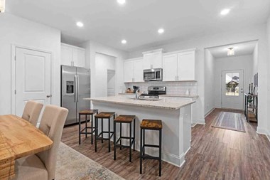 a kitchen with white cabinetry and a large center island with a marble countertop
