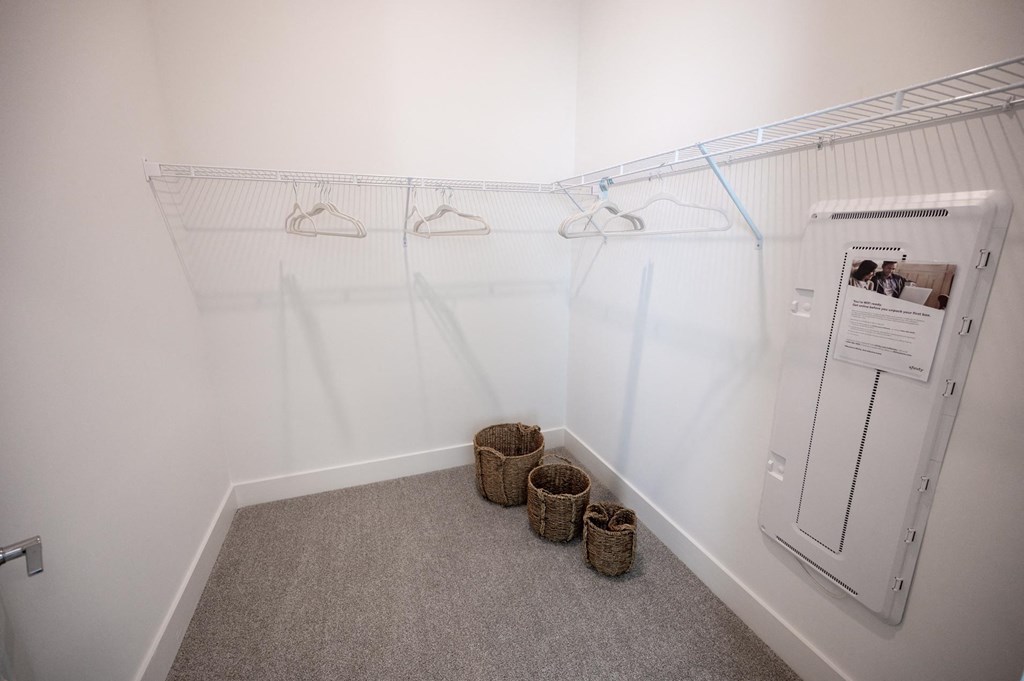a walk in closet with a dryer and baskets on the floor