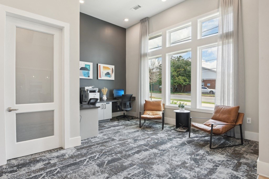 a living room with two chairs and a desk and a window