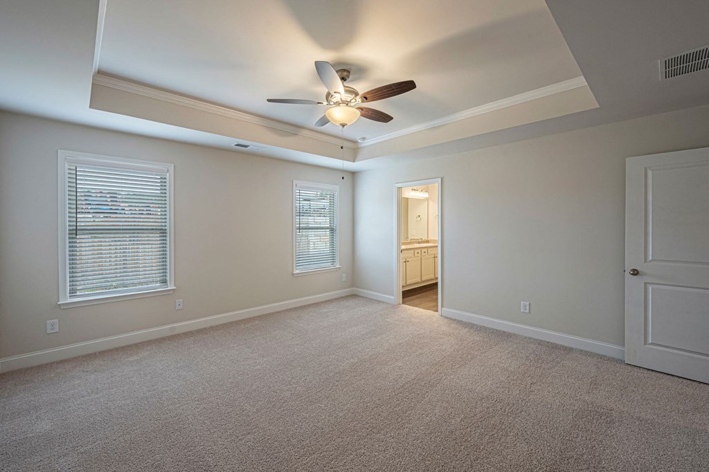 an empty living room with a ceiling fan and a door to a bathroom