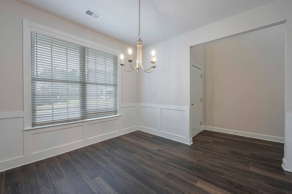 an empty living room with a large window and a chandelier