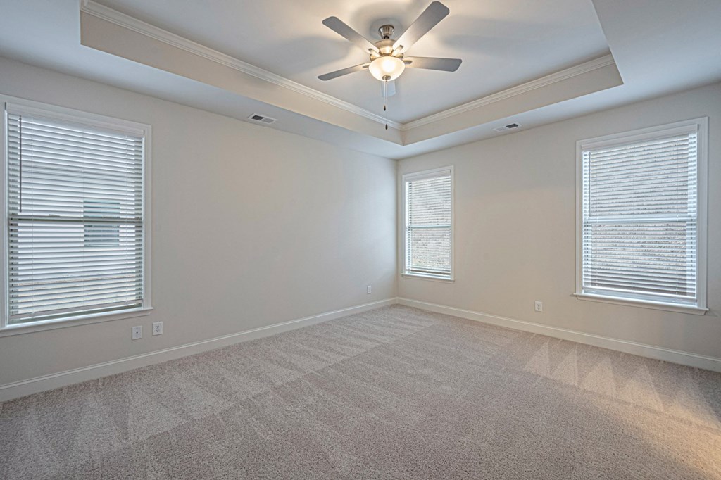 an empty living room with a ceiling fan and two windows