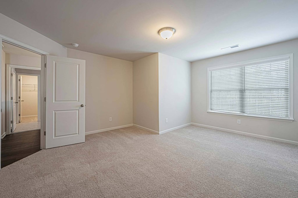 an empty living room with a large window and a door to a hallway