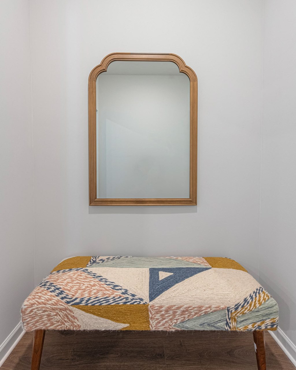 a mirror hanging on a wall above a stool in a room