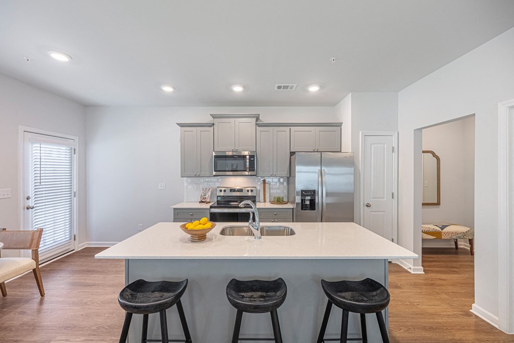 a kitchen with a center island and three stools in front of a kitchen counter