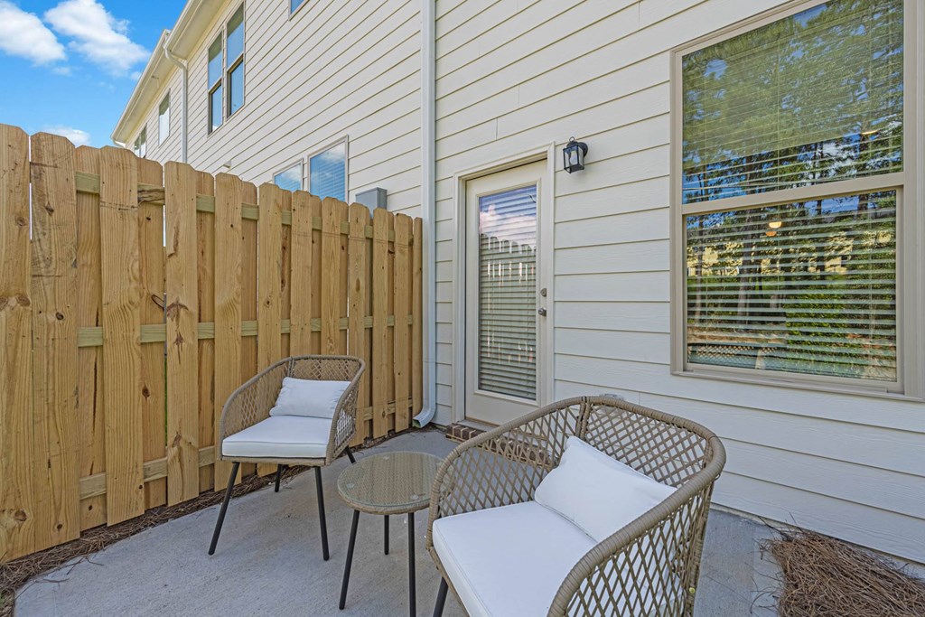 a patio with a fence and two chairs and a table