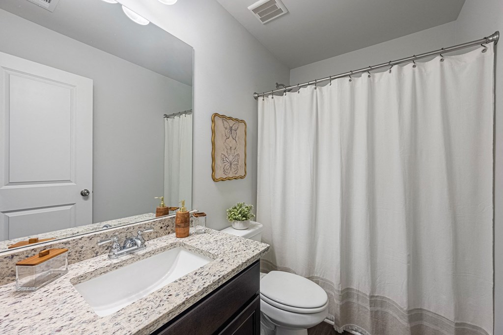a bathroom with a white shower curtain and a sink and a toilet