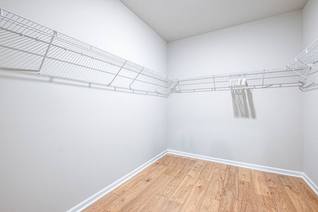 an empty room with white walls and a wooden floor and an empty mirrored closet