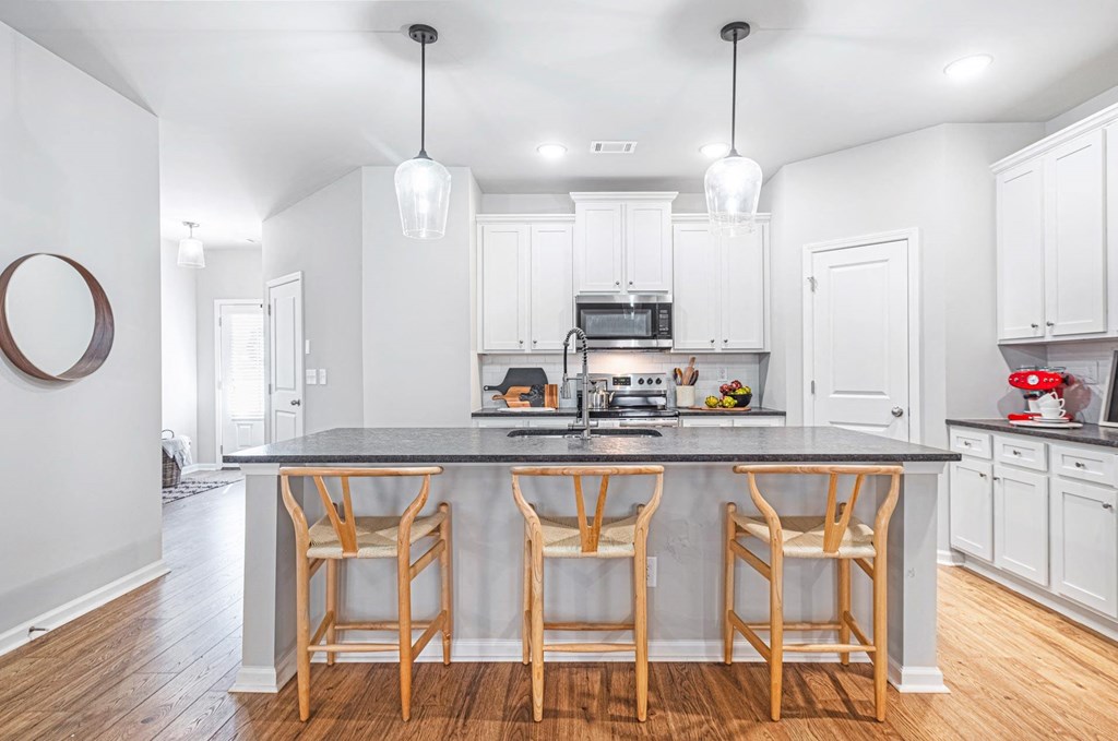 a kitchen with a large island with three chairs