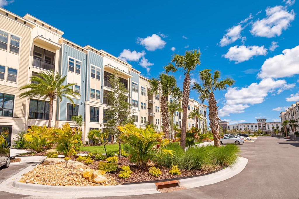 an empty parking lot with palm trees in front of an apartment building