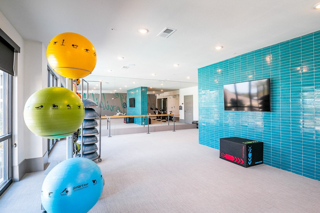 a gym with blue and yellow spheres and a television on the wall