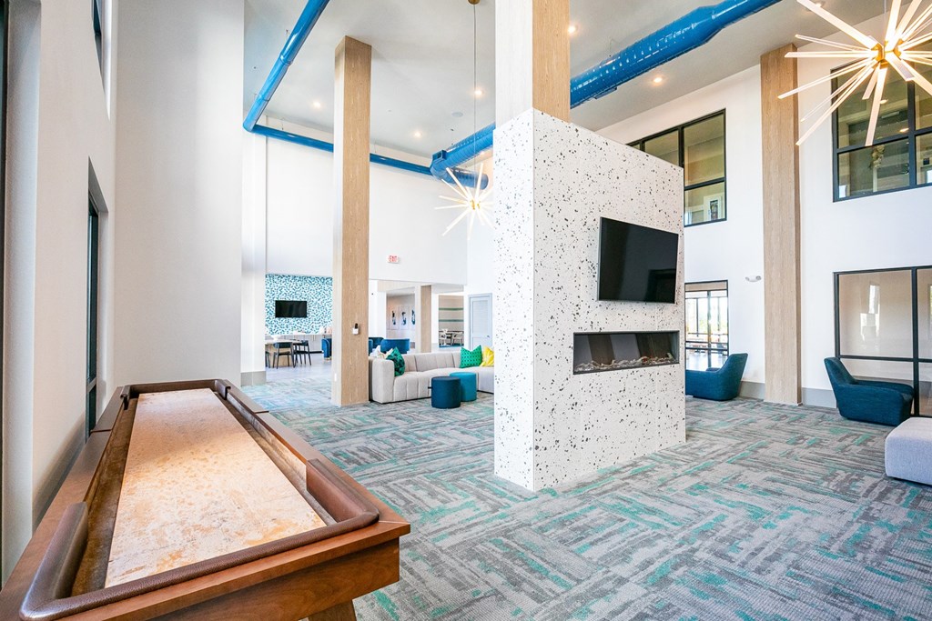 a large lobby with a shuffleboard table and a fireplace