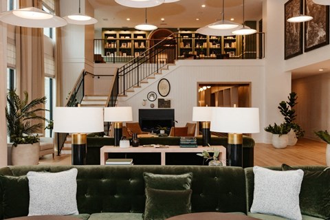 a living room with couches and lamps and a staircase