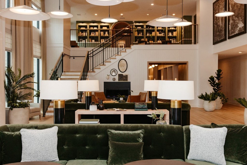 a living room with couches and lamps and a staircase