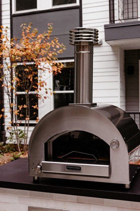 a pizza oven sitting in front of a house
