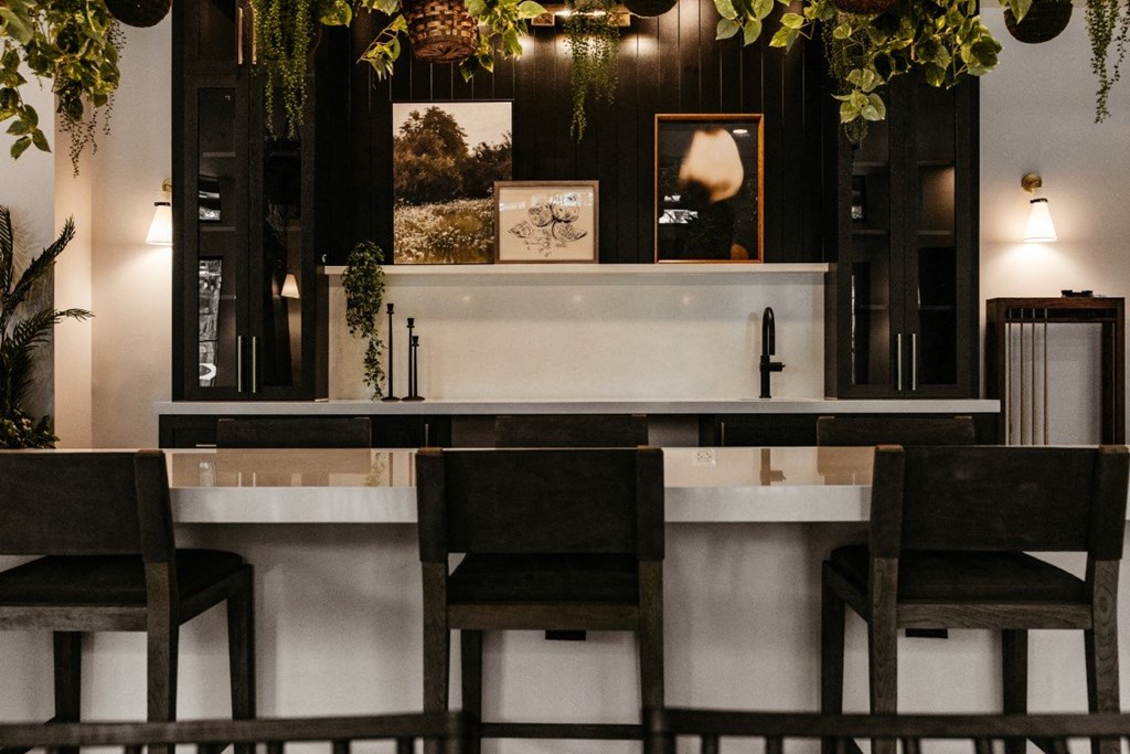 a bar with a sink and chairs in front of it