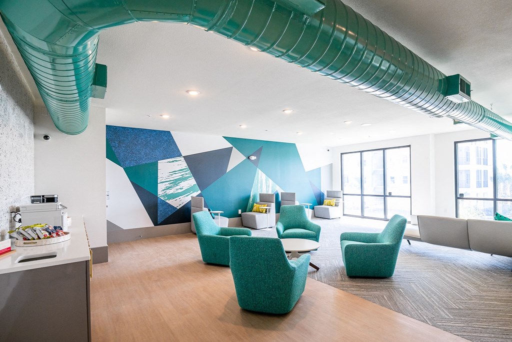 a room with couches and chairs and a wall with a mural in the background