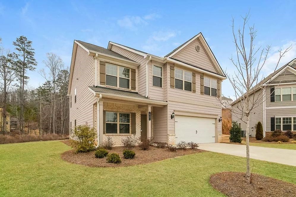 a beige house with a white garage door on a lawn