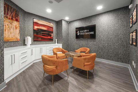 A waiting area with two orange chairs and a sign that says "Society Westshore.".