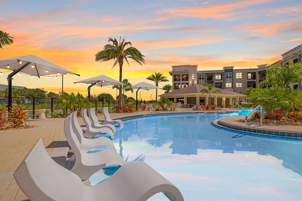 the sun sets over a swimming pool at the resort