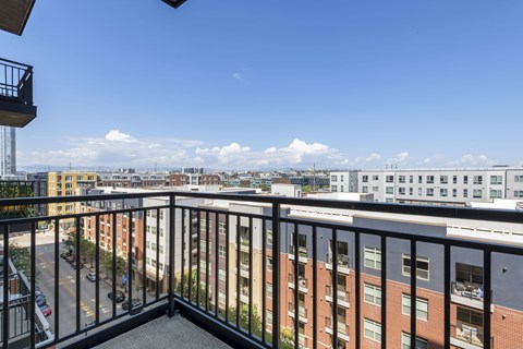 A balcony overlooks a cityscape with buildings and a clear blue sky.