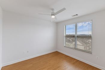a bedroom with a large window and a ceiling fan