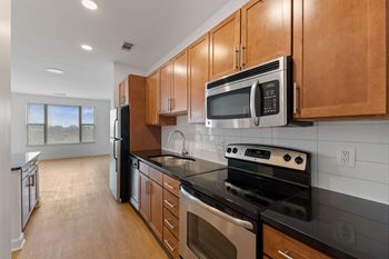 an empty kitchen with wood cabinets and black counter tops and stainless steel appliances