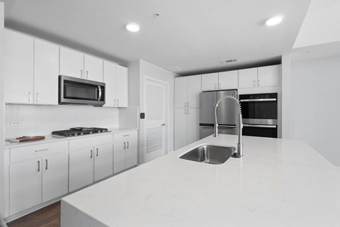 A modern kitchen with white cabinets and a white countertop.